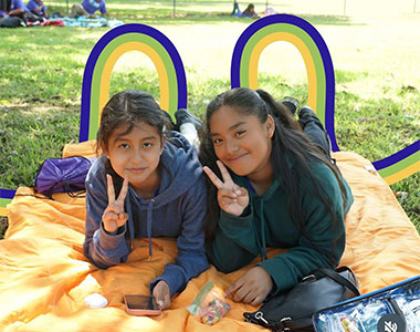 Two young girls smiling with illustrative lines across image